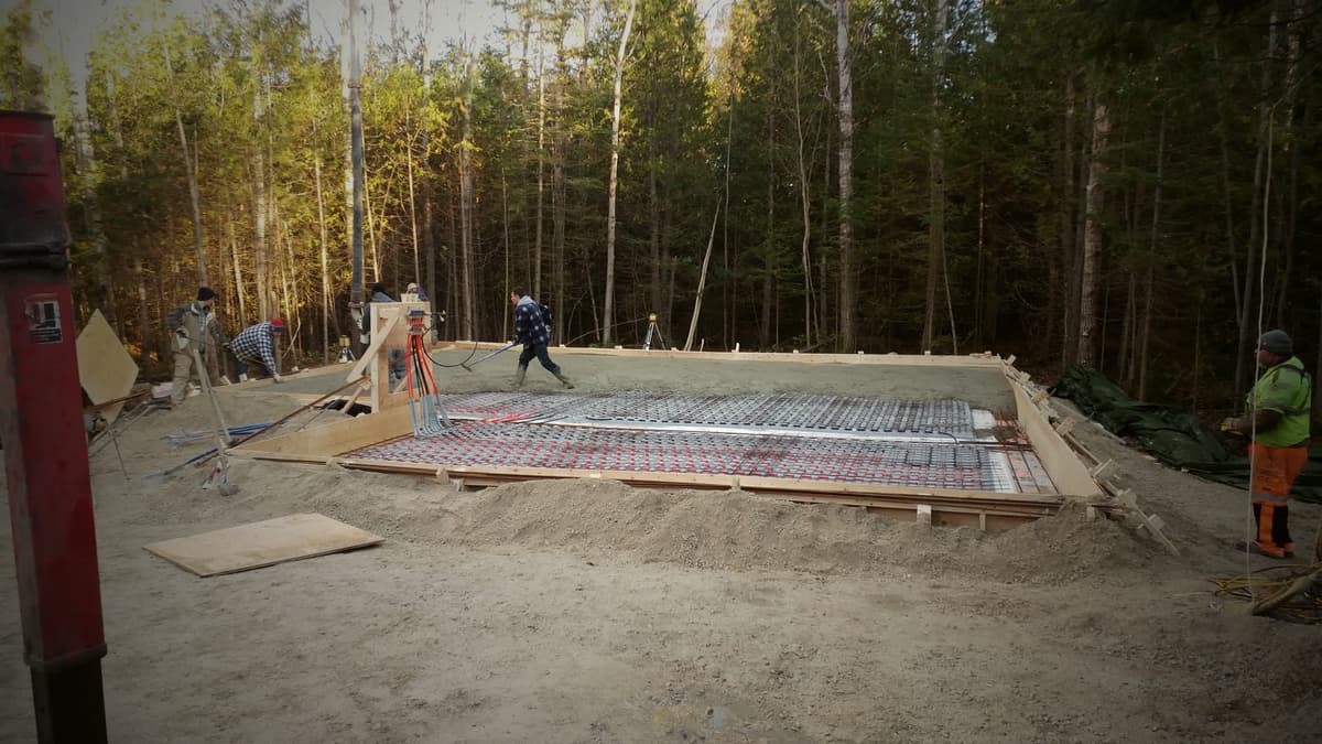 Crew placing concrete for a heated slab in a forest clearing