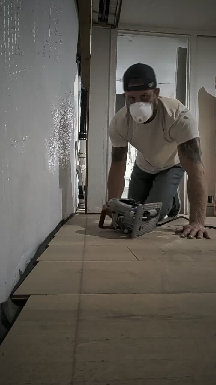 Cameron laying flooring in a basement that another contractor left unfinished