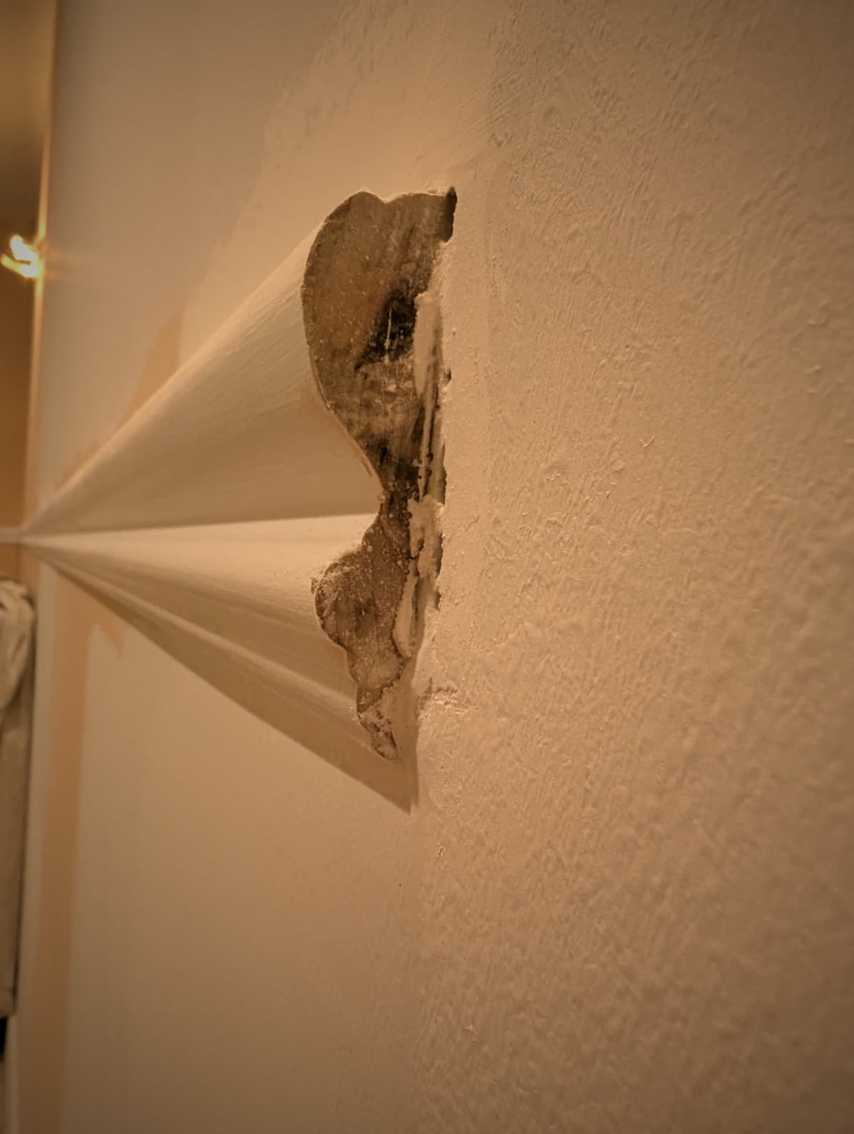 Water damaged drywall at a ceiling corner, opened up and left unrepaired
