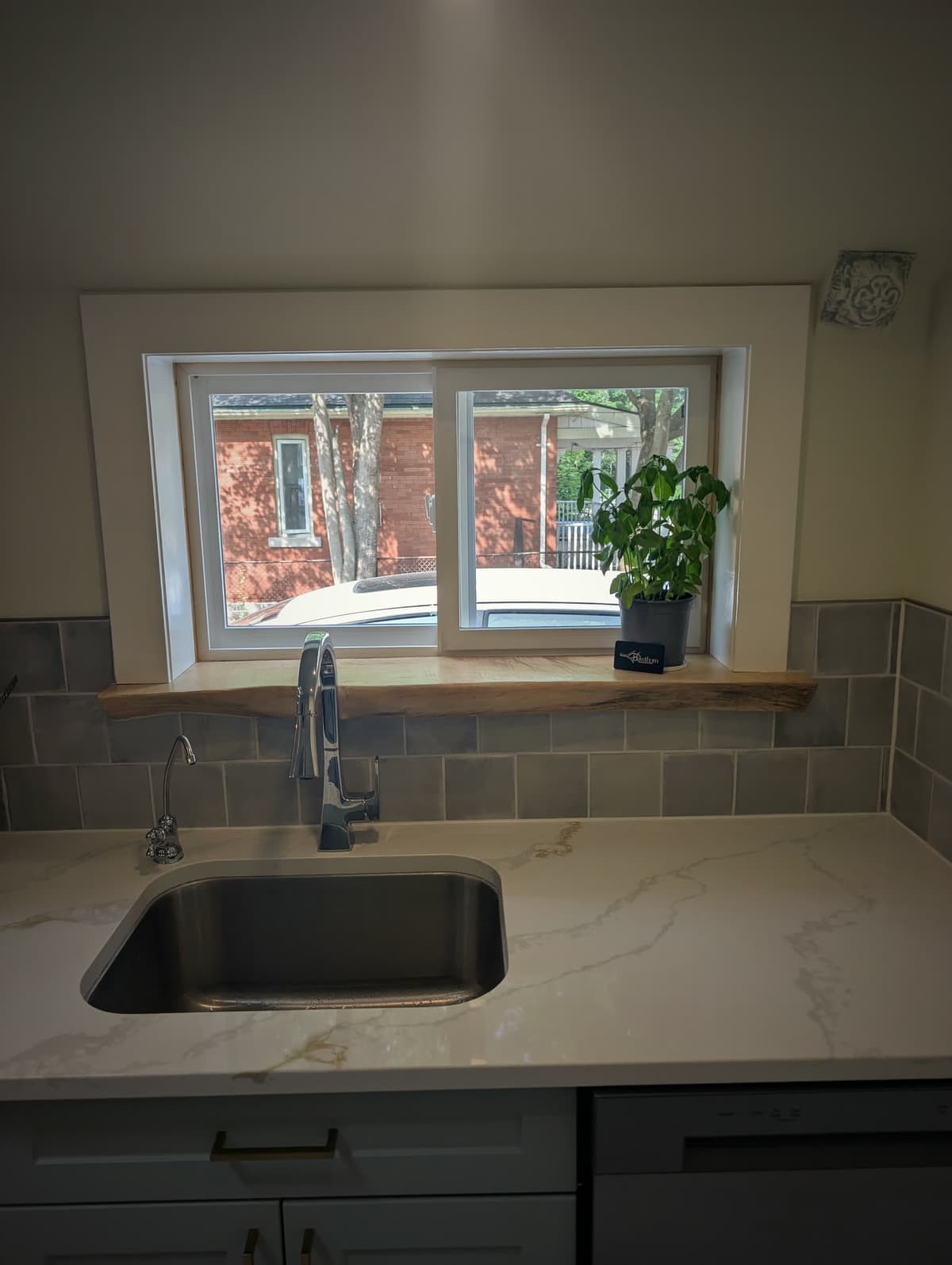 Live-edge wood window sill set against a quartz counter above a kitchen sink